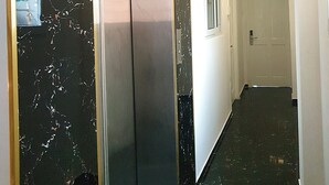 A hallway with a marble wall, an elevator, and a door marked with the number 401.