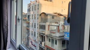 A view from a window with curtains, overlooking a multi-story building with balconies and signage for a hotel.