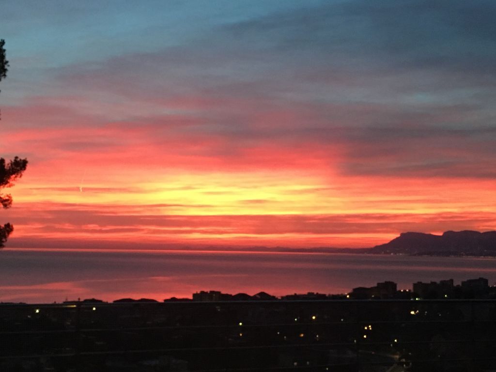 A sunset over a cityscape with buildings silhouetted against the sky.