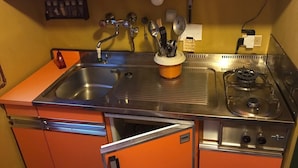 A compact kitchen with a sink, a gas stove, and orange cabinets. - A comfortable vacation in Aprica - Cable car and swimming pool 100 meters away (Aprica)
