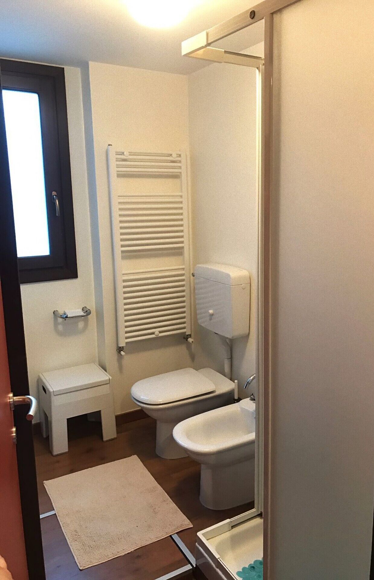 A small, compact bathroom with a toilet, bidet, and a small sink.