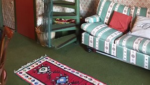A room with a spiral staircase, a patterned wallpaper, a green sofa with red cushions, and a red door. - A comfortable vacation in Aprica - Cable car and swimming pool 100 meters away (Aprica)