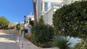 A coastal building with a paved walkway, palm trees, and a clear blue sky. - VILLA on a golf course close to the beach, swimming pool 50 metres away, WIFI fibre.  (BUDENS)