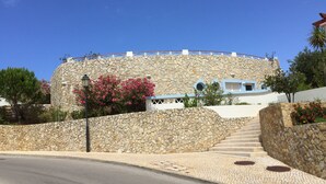 A stone building with a circular design, a staircase leading up to a white entrance, and a clear blue sky. - VILLA on a golf course close to the beach, swimming pool 50 metres away, WIFI fibre.  (BUDENS)