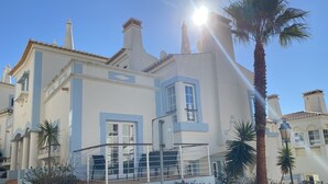 A two-story building with a balcony, a clear sky, and a palm tree. - VILLA on a golf course close to the beach, swimming pool 50 metres away, WIFI fibre.  (BUDENS)