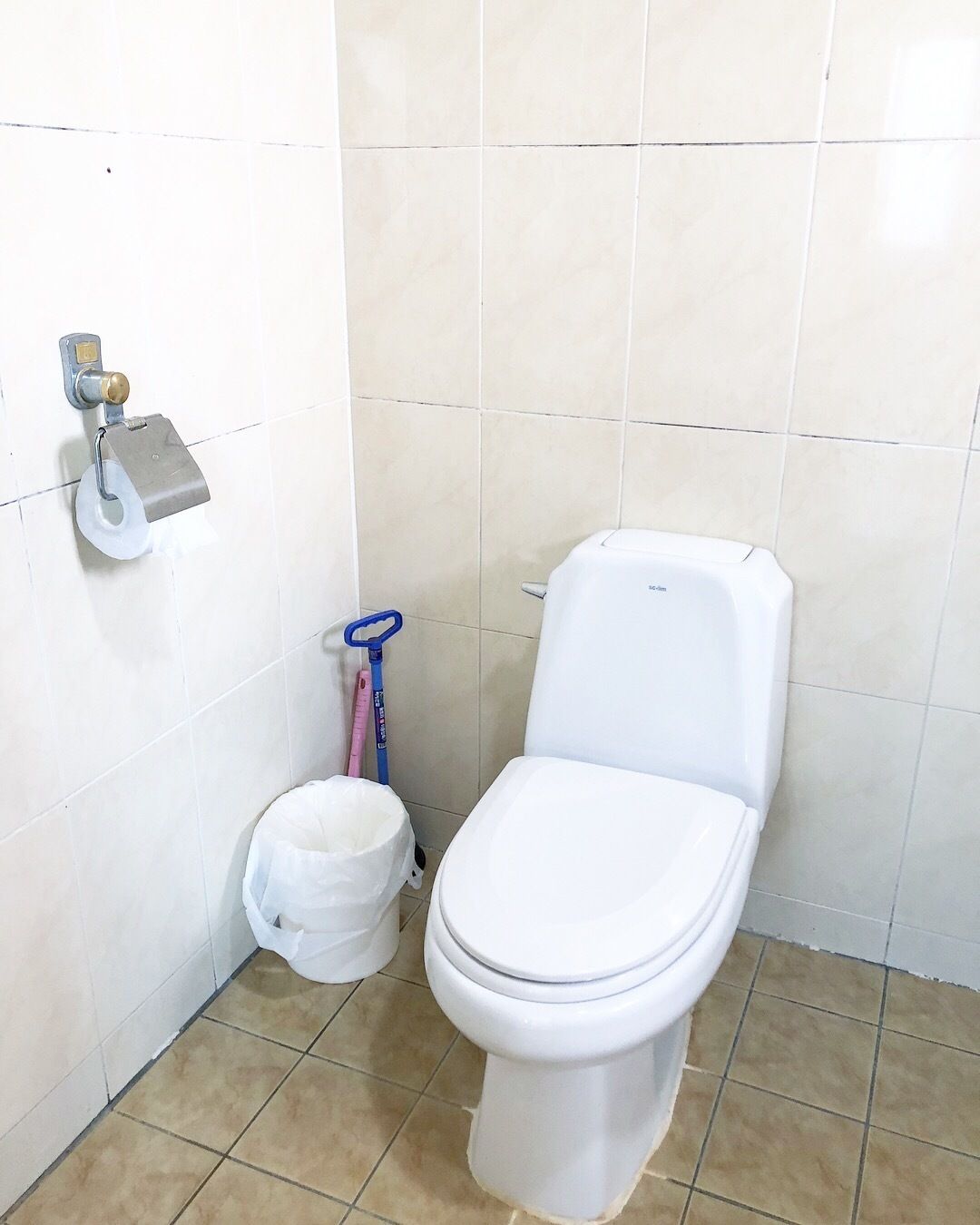 A small, clean bathroom with a toilet, a bidet, and a hand dryer.