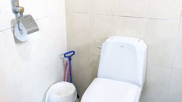 A small, clean bathroom with a toilet, a bidet, and a hand dryer.