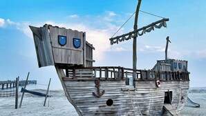 Estructura de barco de madera con un aro salvavidas, un mástil y una cubierta.