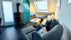 Una sala de estar moderna con un sofá, una mesa de centro, un televisor y una chimenea.