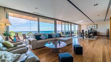 Een ruime woonkamer met een groot raam met uitzicht op een prachtig panorama, een comfortabele bank, een eethoek en een houten vloer.