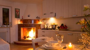 Una cocina acogedora con chimenea, armarios de madera y una mesa de comedor para dos personas, con una vela.