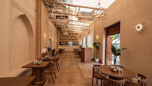 A spacious restaurant with high ceilings, exposed ductwork, and a variety of seating arrangements including tables and booths. - Ramee Techome (Mumbai)