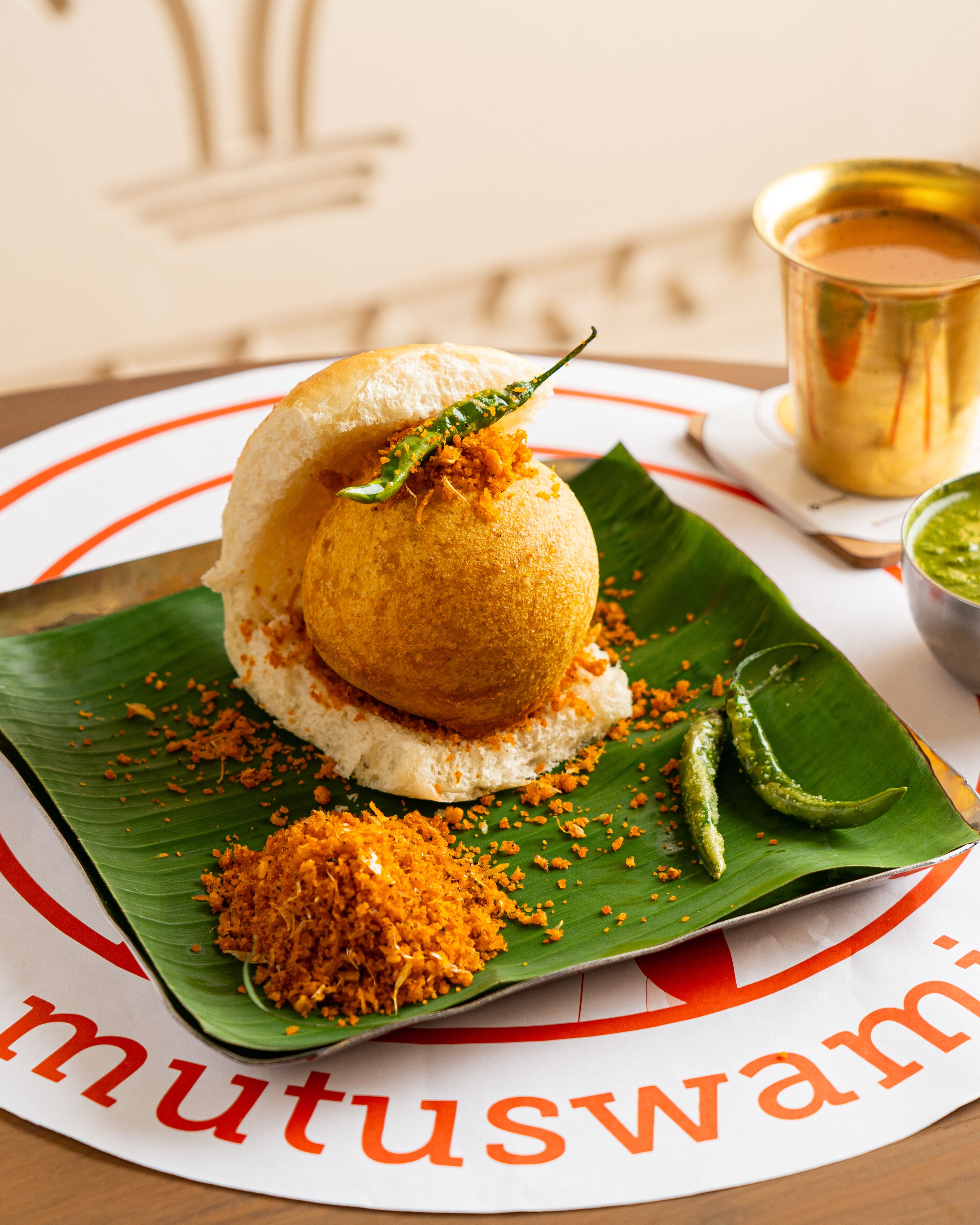 Plato tradicional del sur de la India servido sobre una hoja de plátano, con una taza de té al fondo.