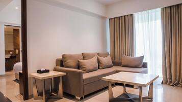 A modern living room with a sofa, two side tables, and a large window with curtains.