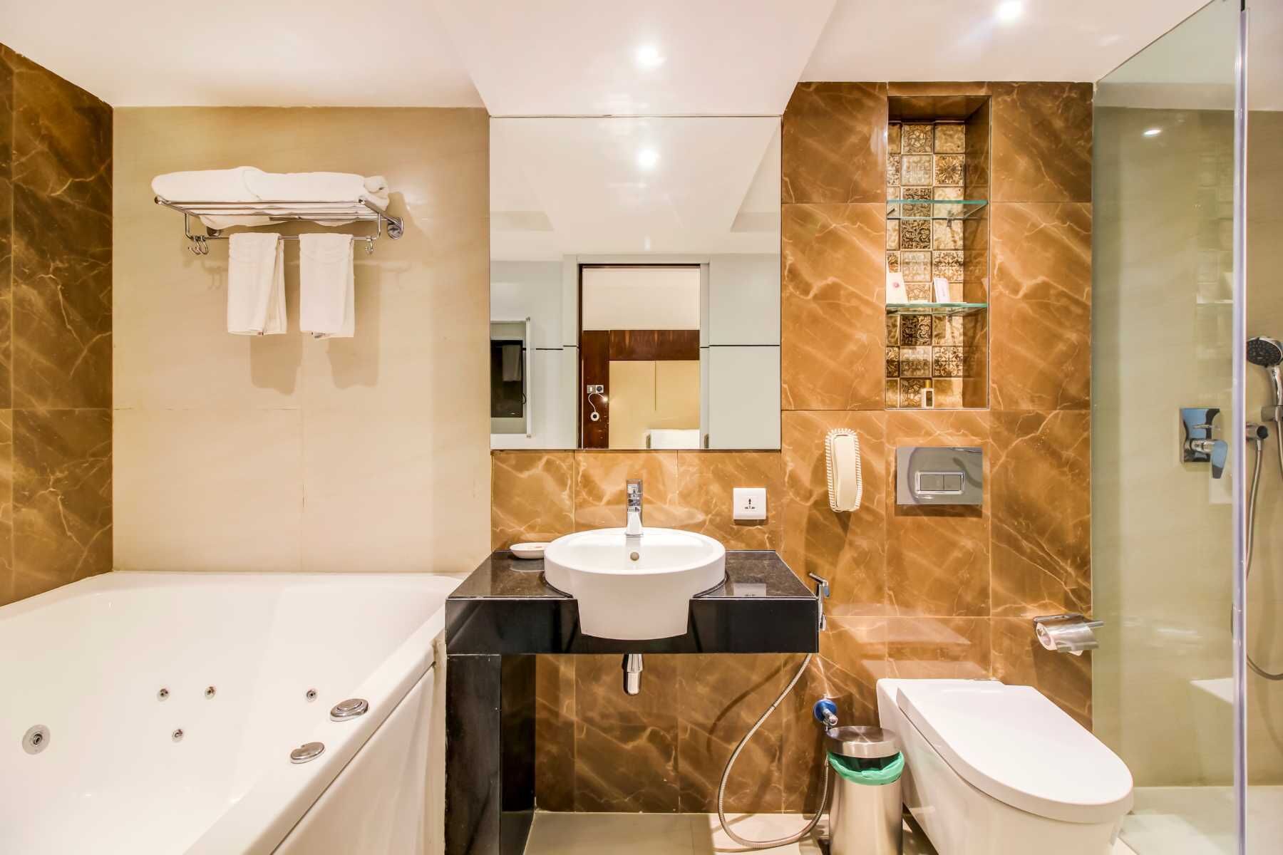 A modern bathroom with a bathtub, sink, toilet, and glass-enclosed shower.