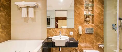 A modern bathroom with a bathtub, sink, toilet, and glass-enclosed shower.