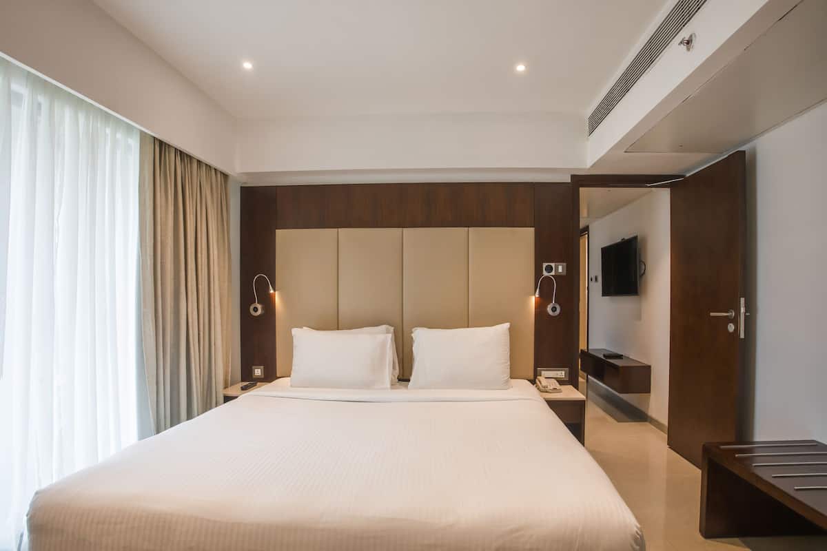 A modern hotel room with a large bed, a TV, and a desk.
