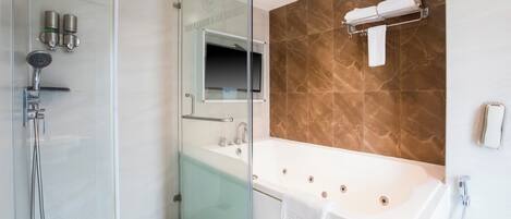 Un baño moderno con ducha envuelta en vidrio, una bañera grande y un muro con azulejos de mármol.