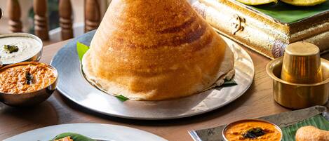A variety of South Indian dishes including a cone-shaped dosa, coconut chutney, and a bowl of sambar.