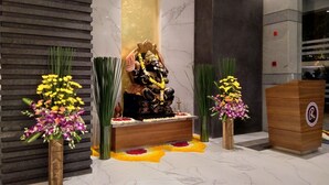 A reception area with a statue, floral arrangements, and a podium. - Ramee Techome (Mumbai)