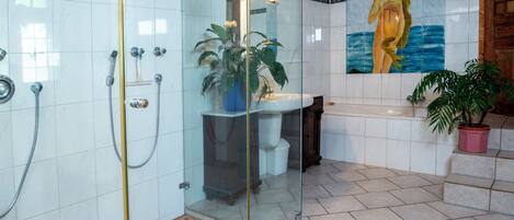 Un baño moderno con cabina de ducha de vidrio, lavamanos, bañera y un mural decorativo.