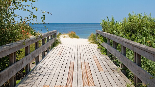A wooden boardwalk leading to a beach with clear blue water. - Apartment beach life. 2 bedrooms, high quality furnishings, great sea views! (Börgerende-Rethwisch)