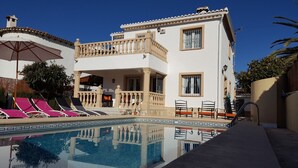 Un bâtiment à deux étages doté d’une piscine, de chaises longues et d’un patio couvert.