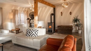 A cozy living room with a white sofa, an orange armchair, a fireplace, and a large window.