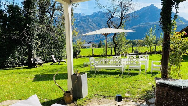 A patio with outdoor furniture, a pergola, and a view of mountains.