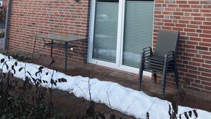 En byggnad av tegel med ett tak täckt av takpannor, en skjutdörr av glas och en satellantenn.
