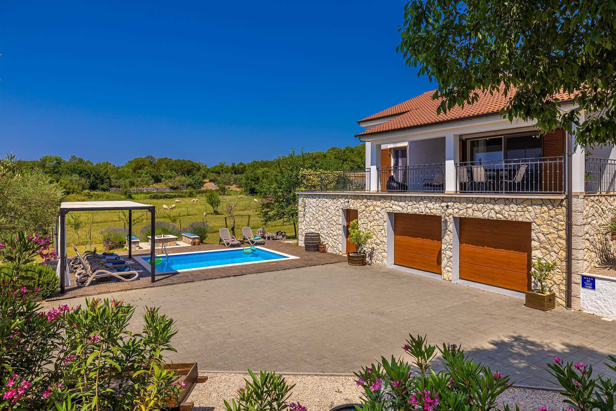 A two-story house with a stone facade, a swimming pool, and a balcony with outdoor furniture.