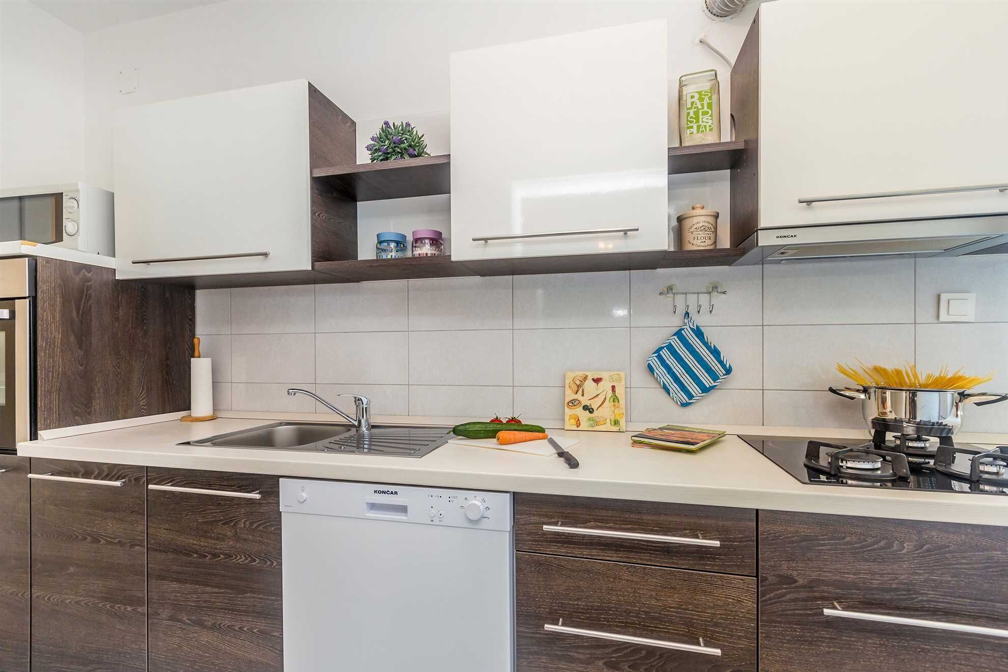 Une cuisine moderne avec des armoires blanches, un lave-vaisselle encastré et une cuisinière à gaz.