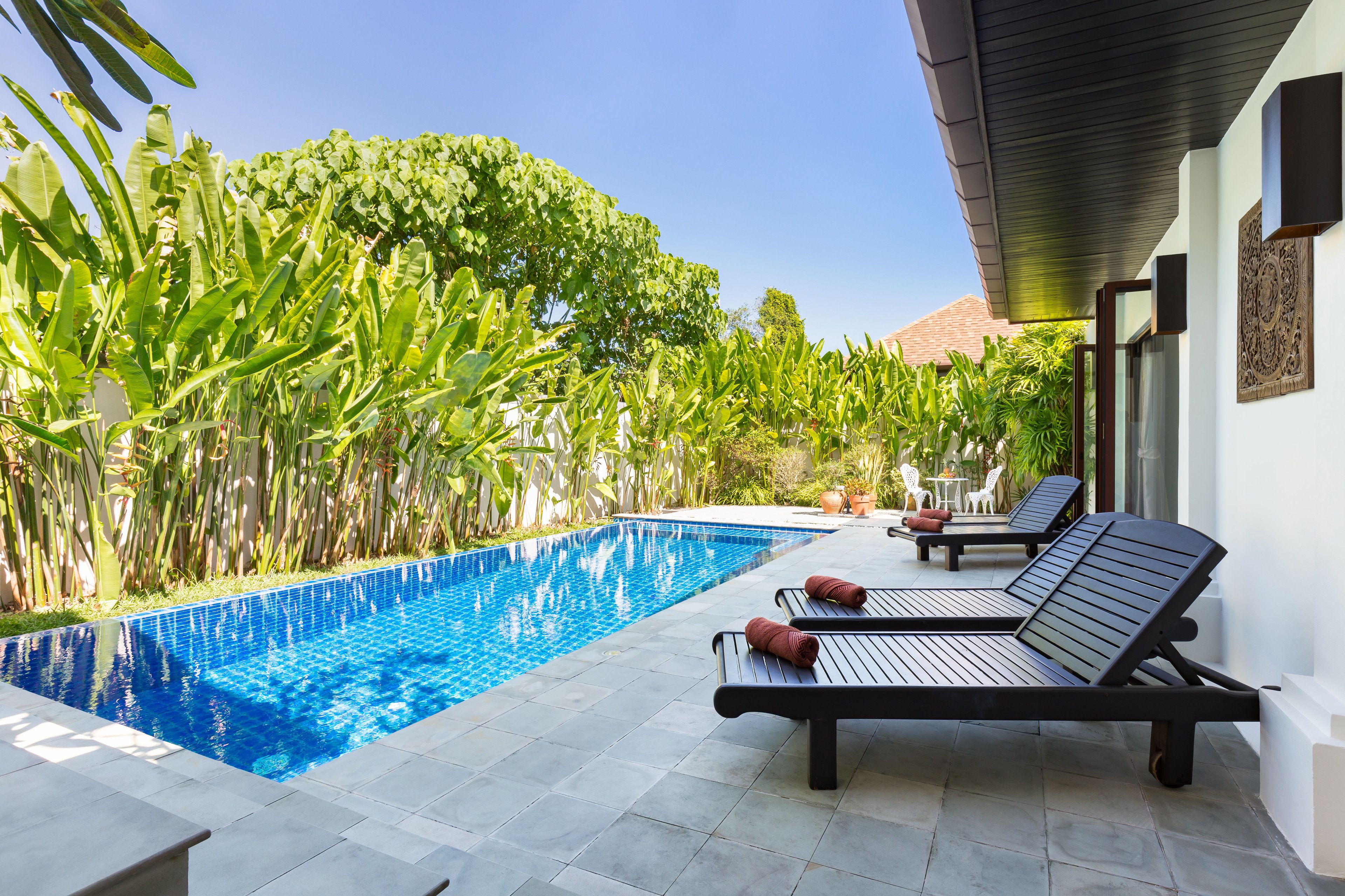 A swimming pool with lounge chairs and a tiled patio area.