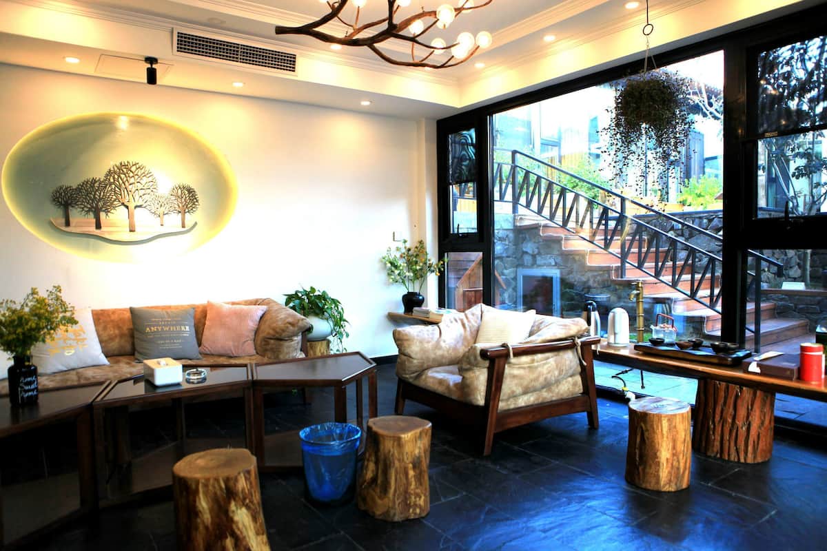 A cozy interior with a sofa, armchairs, a coffee table, and a large window overlooking a staircase.