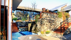 A stone wall with a wooden staircase leading to a pool area. - Carpenter's Rustic Courtyard-Great Wall (Huairou)