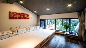 A large bed with a wooden floor, a window with a view of greenery, and a red artwork on the wall. - Carpenter's Rustic Courtyard-Great Wall (Huairou)