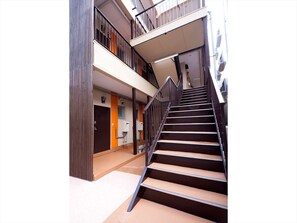 Een modern interieur met een trap die naar een verdieping leidt, met een metalen leuning en een beigekleurige vloer.