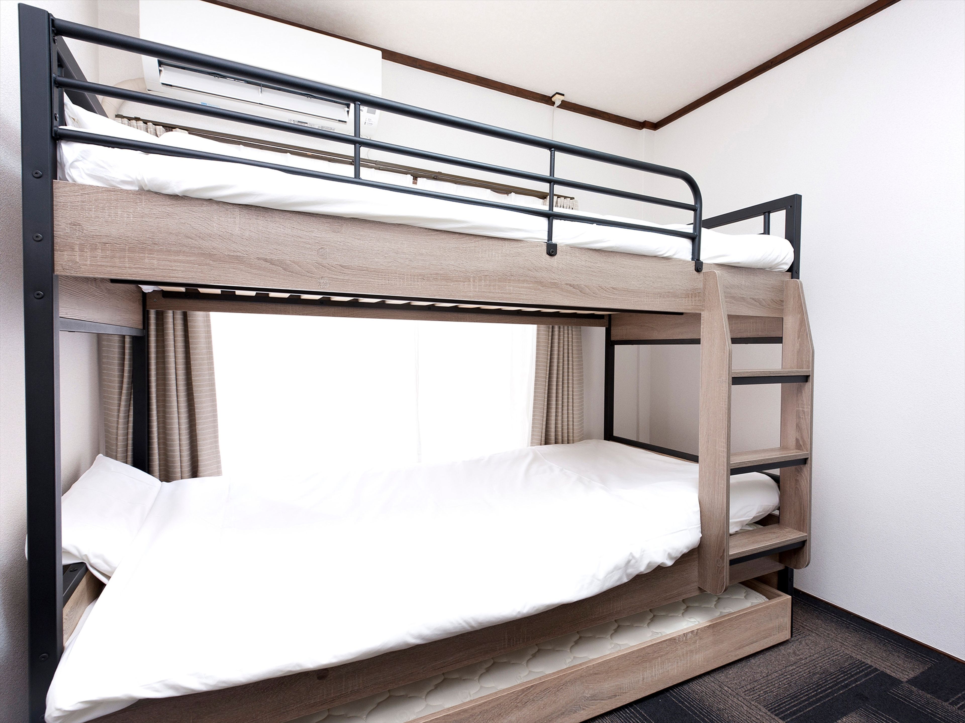 Ein Stockbett mit Holzrahmen, weißer Bettwäsche und einem Fenster mit Vorhängen.
