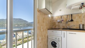 Uma cozinha com máquina de lavar, pia e vista para um corpo de água e montanhas.