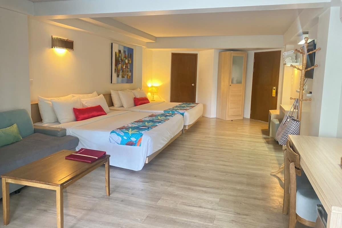 Een hotelkamer met een groot bed, een bank, een kleine tafel en een houten vloer.