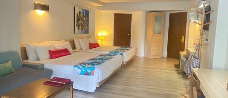 A hotel room with a large bed, a sofa, a small table, and a wooden floor.