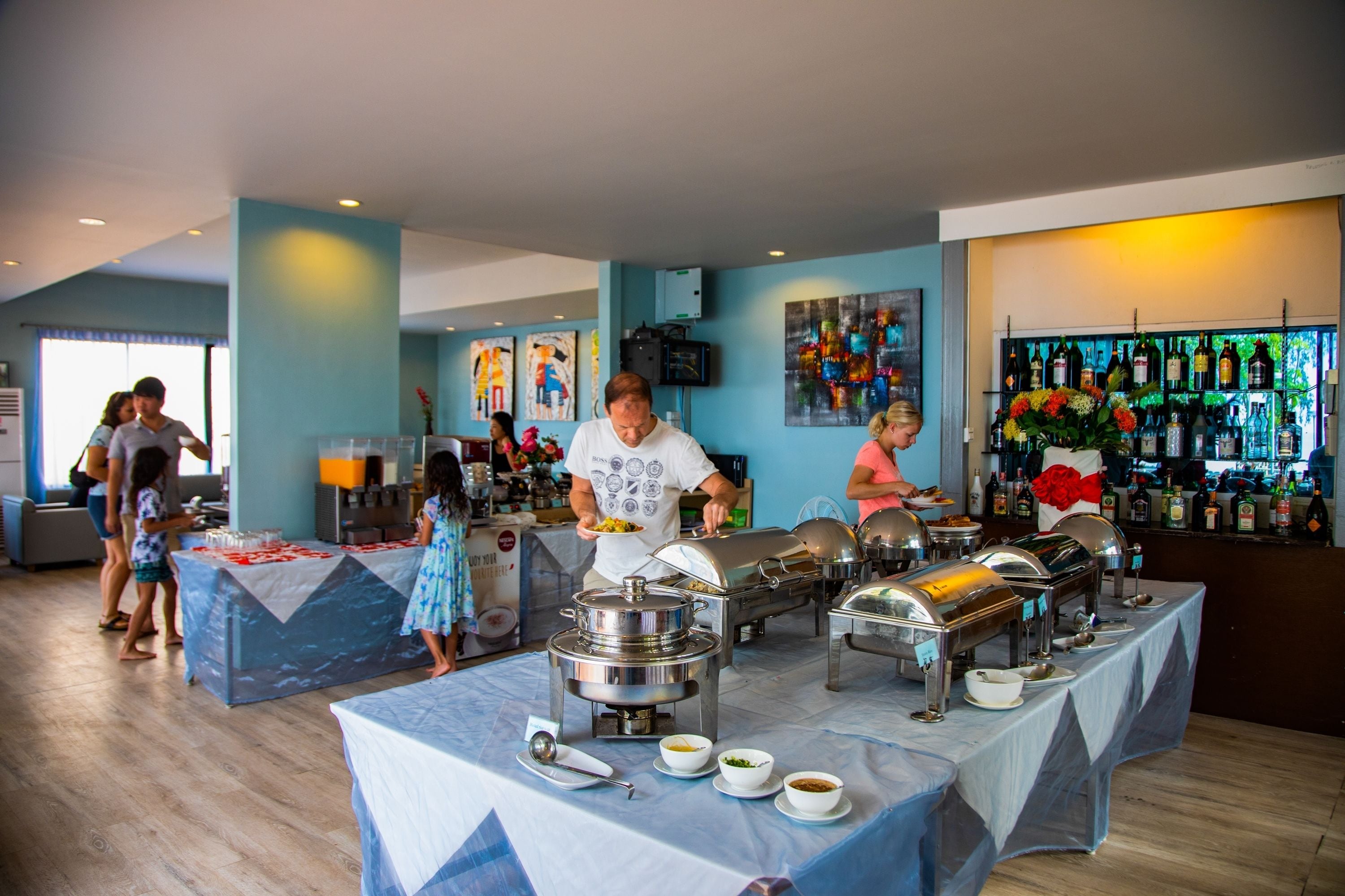 A buffet setup with various food stations, a bar area with bottles, and a group of people dining.