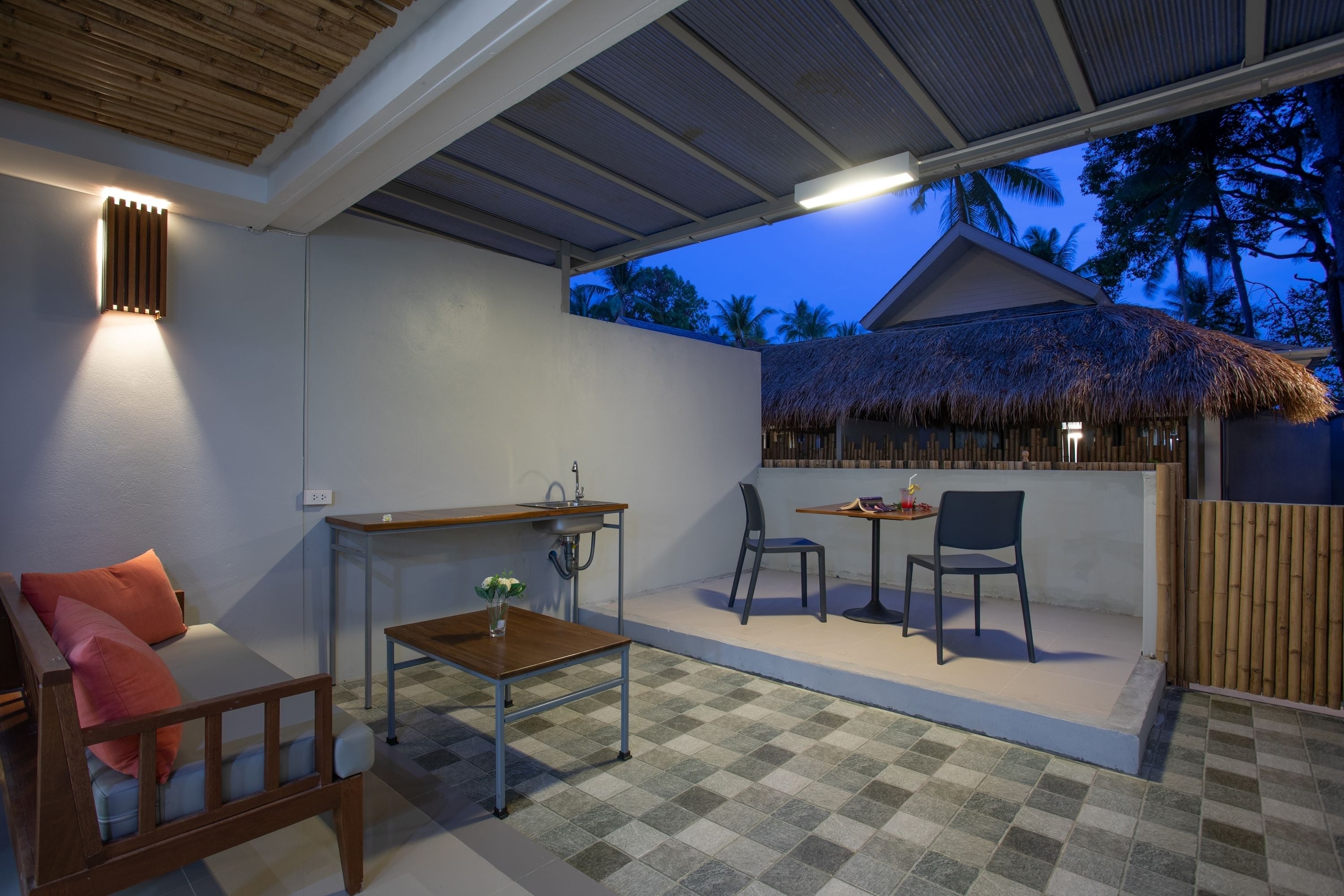 A covered outdoor seating area with a table, chairs, and a sofa.