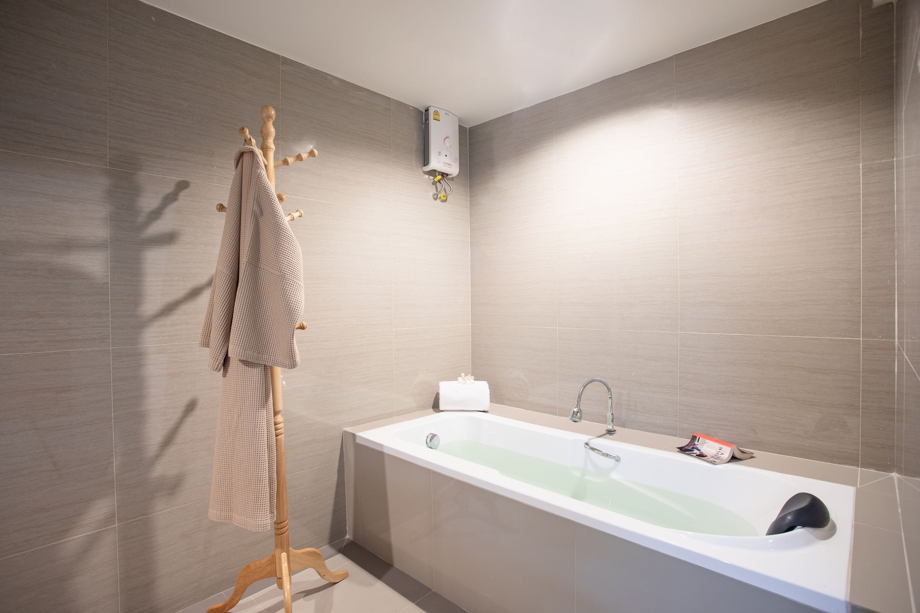 Un baño moderno con una bañera independiente, un perchero y un calentador de pared.