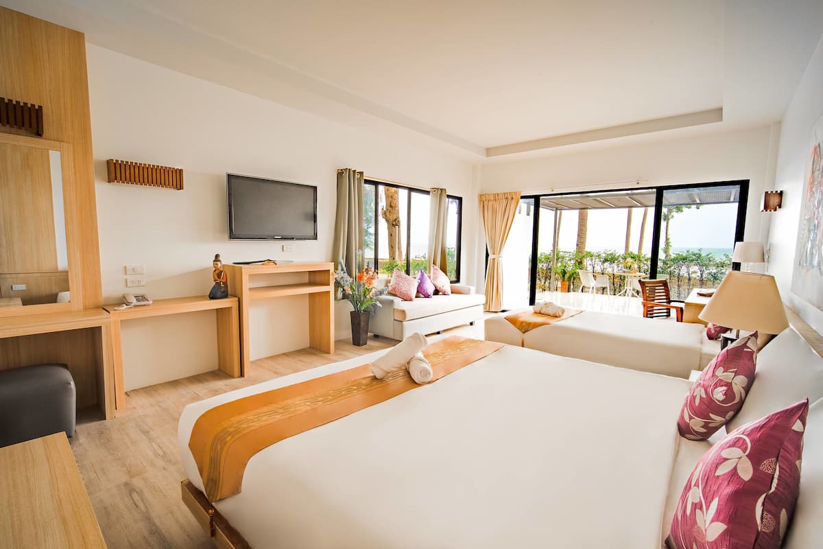 Een hotelkamer met een groot bed, een bureau, een televisie en uitzicht op de oceaan.