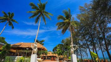 A resort with thatched-roof buildings, palm trees, and outdoor seating areas.