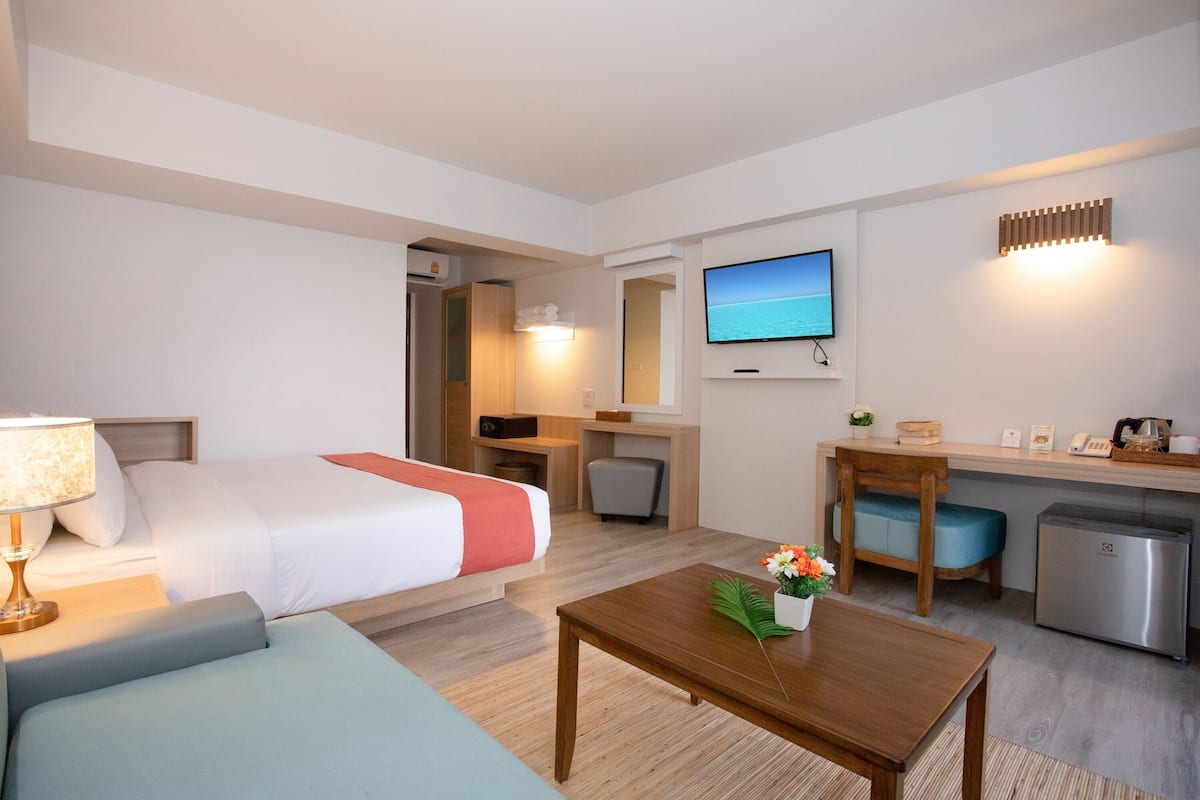 Een hotelkamer met een bed, bureau, televisie, koffiezetapparaat en een koelkast.