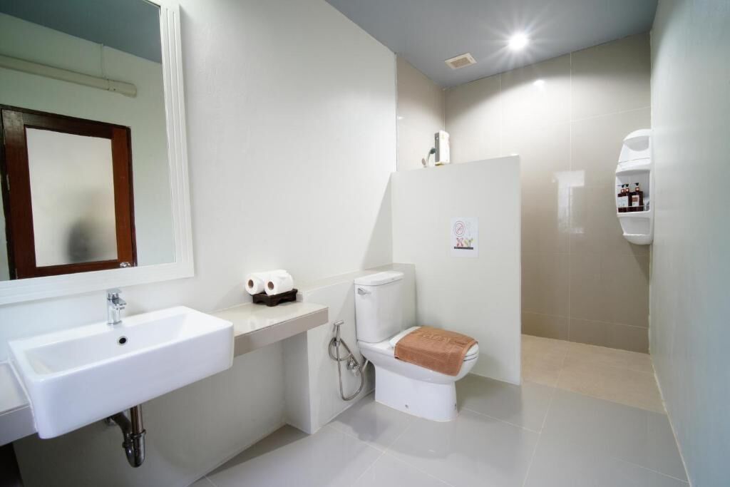 A modern bathroom with a white sink, toilet, and shower area.