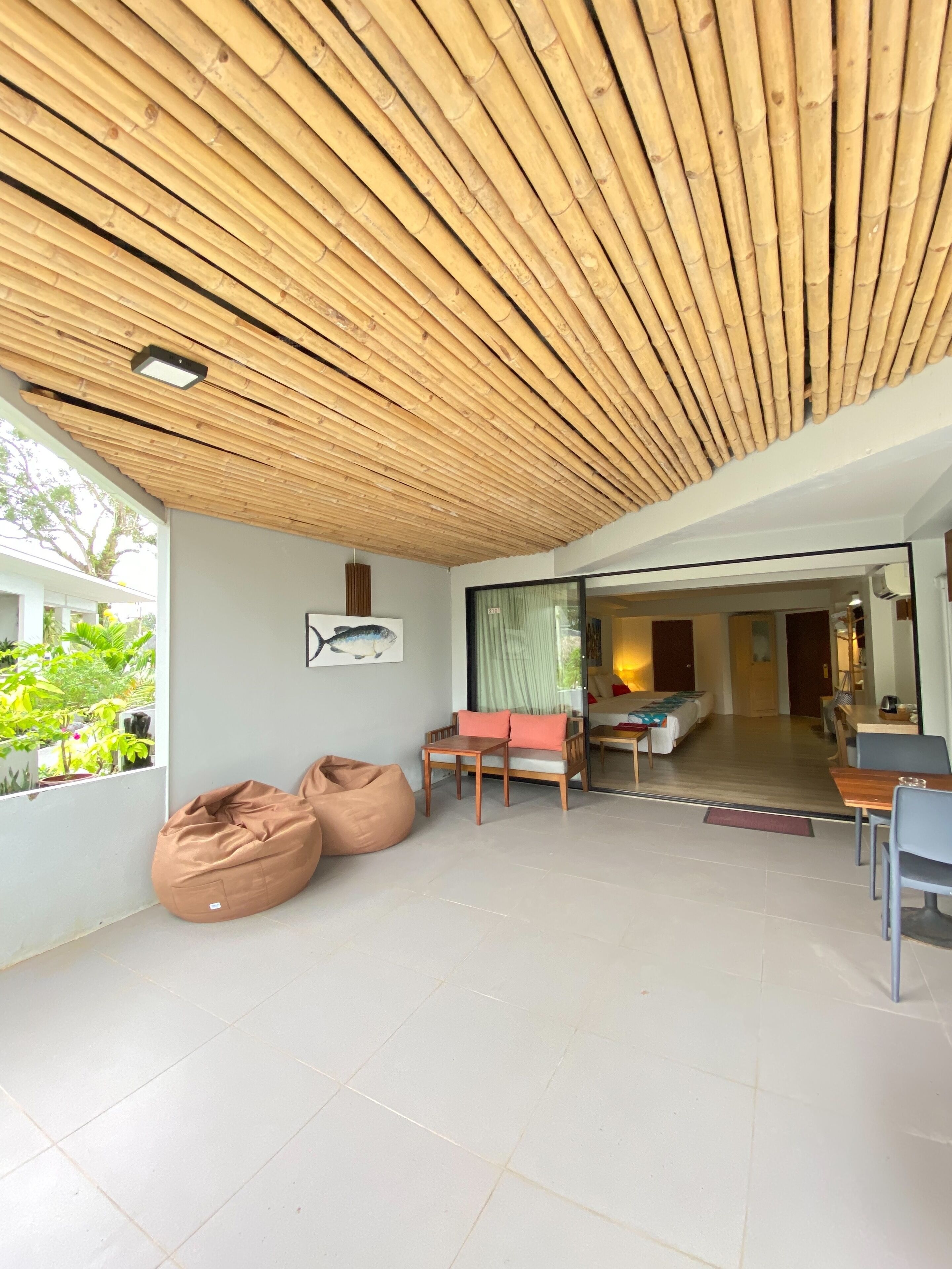 A modern interior with a bamboo ceiling, a seating area with bean bags and a small table, and a view of a garden outside.