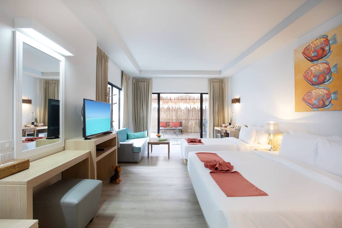 Een hotelkamer met een bed, een bureau, een televisie, een bank en een balkon met uitzicht.